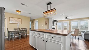 Una cocina moderna con una isla central, suelo de madera e iluminación colgante.