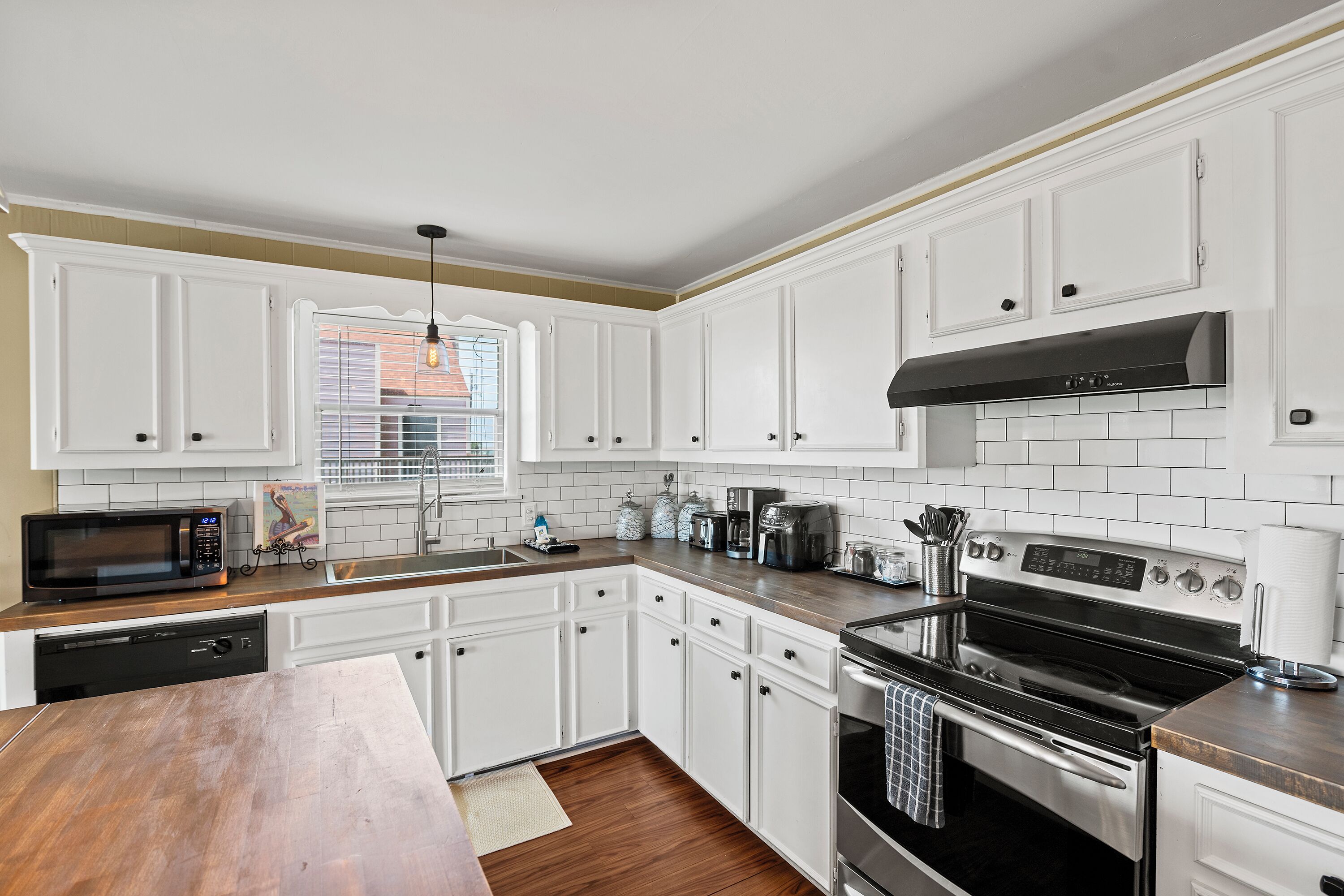 A kitchen with white cabinets, a stainless steel stove, and a microwave.