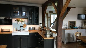 Una cocina con armarios oscuros, una isla de madera, un fregadero y un comedor con mesa y sillas.