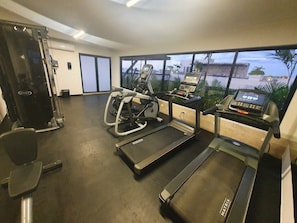 A gym with treadmills, a weight machine, and a rowing machine.