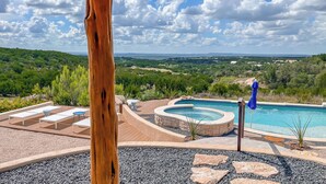 Zona de piscina amb gandules, banyera hidromassatge i vista al paisatge.
