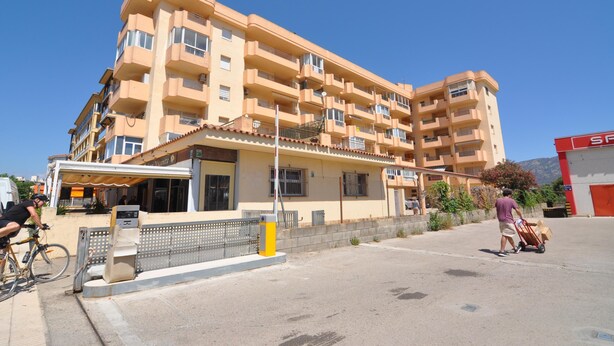 Un hotel de diverses plantes amb balcons, una zona d'estar exterior coberta i una entrada ben visible.