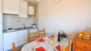 Una cuina compacta amb armaris blancs, un rentaplat i una zona de menjador amb taula per a dues persones.