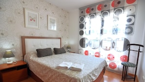 A neatly made bed with pillows, a bedside table with a lamp, and a chair with a cushion. - Apartment for rent in Roses, Costa Brava! Ideal for 4 people, with pool and WiFi. Book now! (Roses)