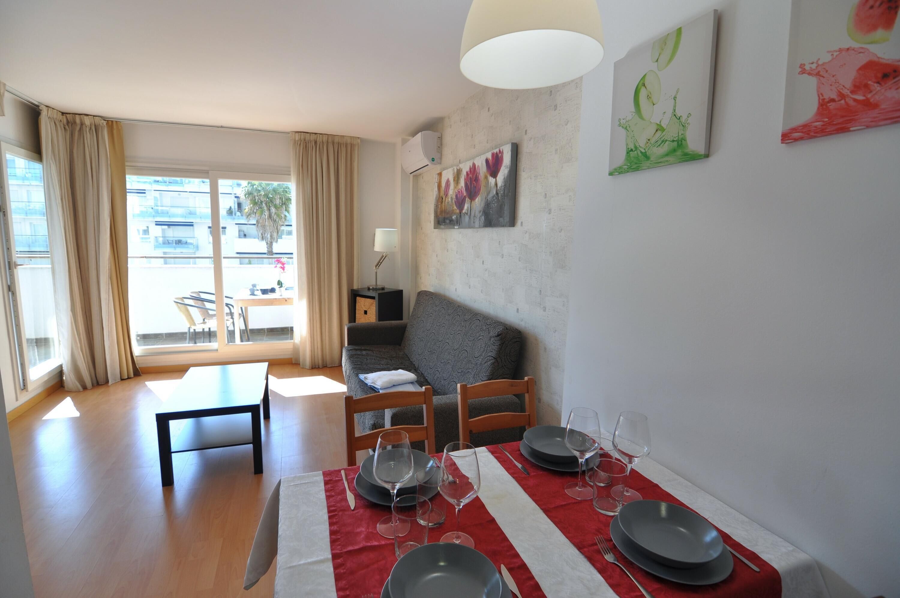 Un coin repas avec une table dressée pour quatre personnes, un canapé et une fenêtre avec des rideaux.