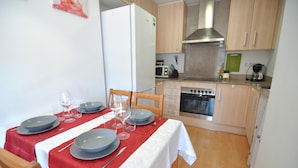 A compact kitchen with a microwave, stove, and oven. There is a dining table set with plates, glasses, and cutlery. - Apartment for rent in Roses, Costa Brava! Ideal for 4 people, with pool and WiFi. Book now! (Roses)