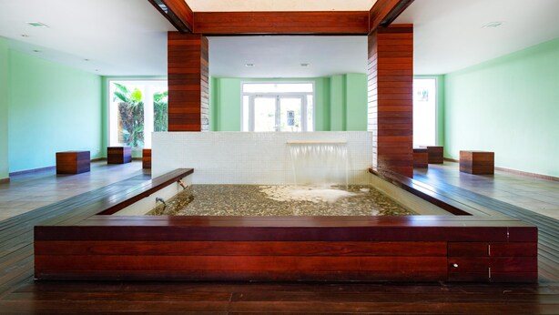 Une salle de bain moderne avec un banc en bois, une petite fontaine et une vue sur l’extérieur.