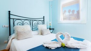 Un lit avec une couvre-lit bleue, des oreillers blancs et une serviette décorative en forme de cygne.
