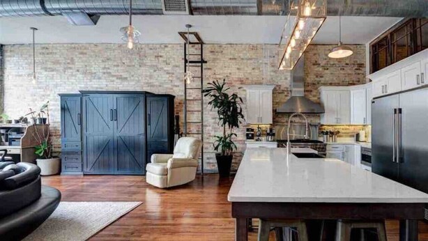 A modern kitchen with a large island, white cabinets, and a brick wall. - Downtown Luxury Traverse City Loft on Union St (Traverse City)
