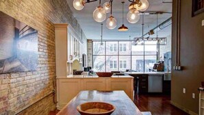 A spacious kitchen with a large island, exposed brick walls, and pendant lighting. - Downtown Luxury Traverse City Loft on Union St (Traverse City)