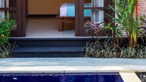 A room with a bed, a painting, and a view of a swimming pool.