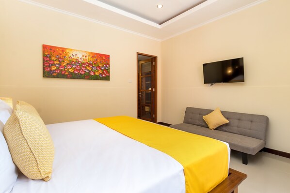 Een hotelkamer met een bed, een bank, een televisie en een schilderij aan de muur.