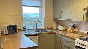 Una cocina compacta con microondas, tostadora, fregadero y cocina.