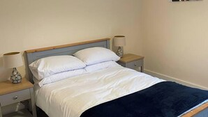 Un dormitorio con una cama, dos mesitas de noche y lámparas.