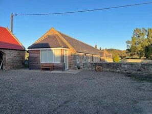Un petit bâtiment d’un seul étage, doté d’un toit en pente, d’un banc à l’extérieur et d’une allée gravillonnée.