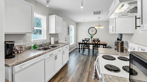 A modern kitchen with white cabinets, a granite countertop, a dining area with a table and chairs, and a stove. - Sleeps 6 - 3 Queen Beds - 2 Mi Wake Forest + Hospital (Winston-Salem)