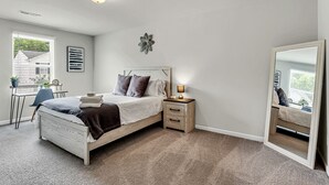 A bedroom with a bed, bedside table, lamp, and a large mirror. - Sleeps 6 - 3 Queen Beds - 2 Mi Wake Forest + Hospital (Winston-Salem)