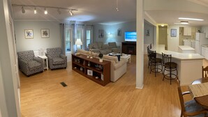 A modern living room with a fireplace, a dining area with a wooden table and chairs, and a kitchen with white cabinets and a stove. - 3 bedroom house that sleeps 9 located in Oceanside Village, Surfside Beach (Surfside Beach)