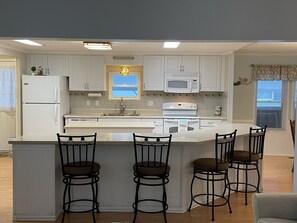A kitchen with a central island, white cabinets, a microwave, and a refrigerator. - 3 bedroom house that sleeps 9 located in Oceanside Village, Surfside Beach (Surfside Beach)