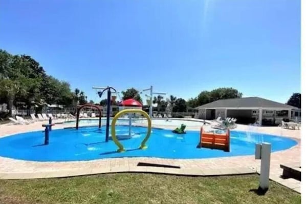 A swimming pool with a slide, a water play area, and a covered pavilion.