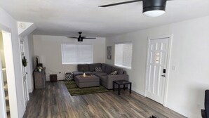 A spacious living room with a grey sectional sofa, a coffee table, and a ceiling fan. - Camelia's cabin (Pinetop)