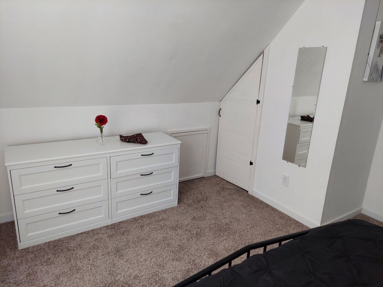 Un dormitorio con un aparador blanco, una cama y un espejo en la pared.