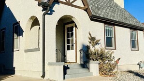 A two-story house with a gabled roof, a chimney, and a front entrance with steps.