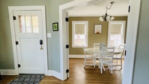 A hallway with a wooden floor leading to a dining area with a white table and chairs.
