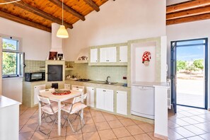 A kitchen with white cabinets, a dining table with chairs, a microwave, a stove, and a refrigerator.