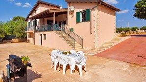 A two-story building with a balcony, a staircase, and a patio area with a table and chairs.