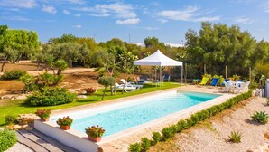 A swimming pool with lounge chairs and a white tent.