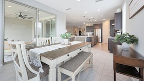 Een moderne keuken met witte kasten, een houten eettafel en een bank.