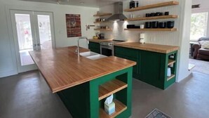 Una cocina moderna con una isla de madera, armarios verdes y estantes empotrados.