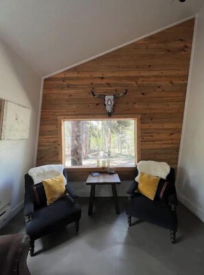 Relax in a serene space with a high ceiling, large window, and comfortable seating area.