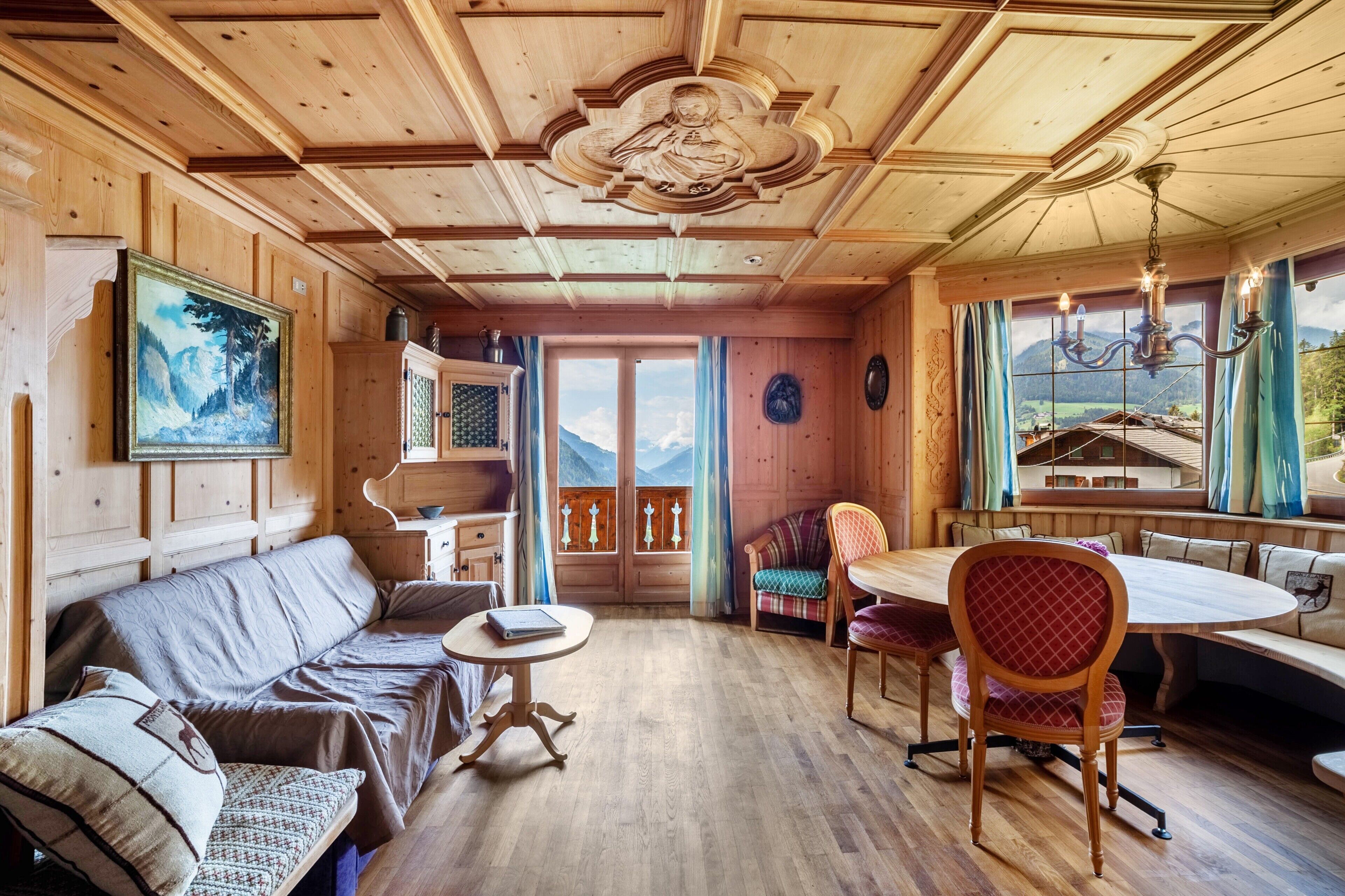 L’intérieur d’un chalet en bois, avec un canapé, une table à manger, des chaises et un tableau.