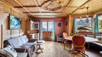 L’intérieur d’un chalet en bois, avec un canapé, une table à manger, des chaises et un tableau.