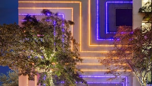 A modern building with illuminated geometric patterns on the facade, a well-maintained entrance area with potted plants, and a clear view of the building's entrance. - Ravatel Home Bac Giang (Bac Giang)