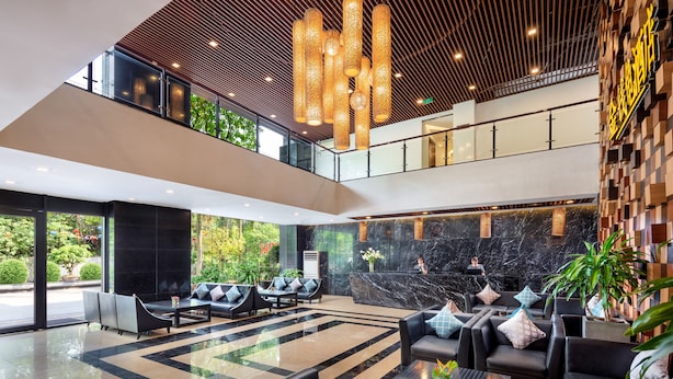 A modern lobby with a glass ceiling, black and beige seating areas, and a reception desk. - Ravatel Home Bac Giang (Bac Giang)