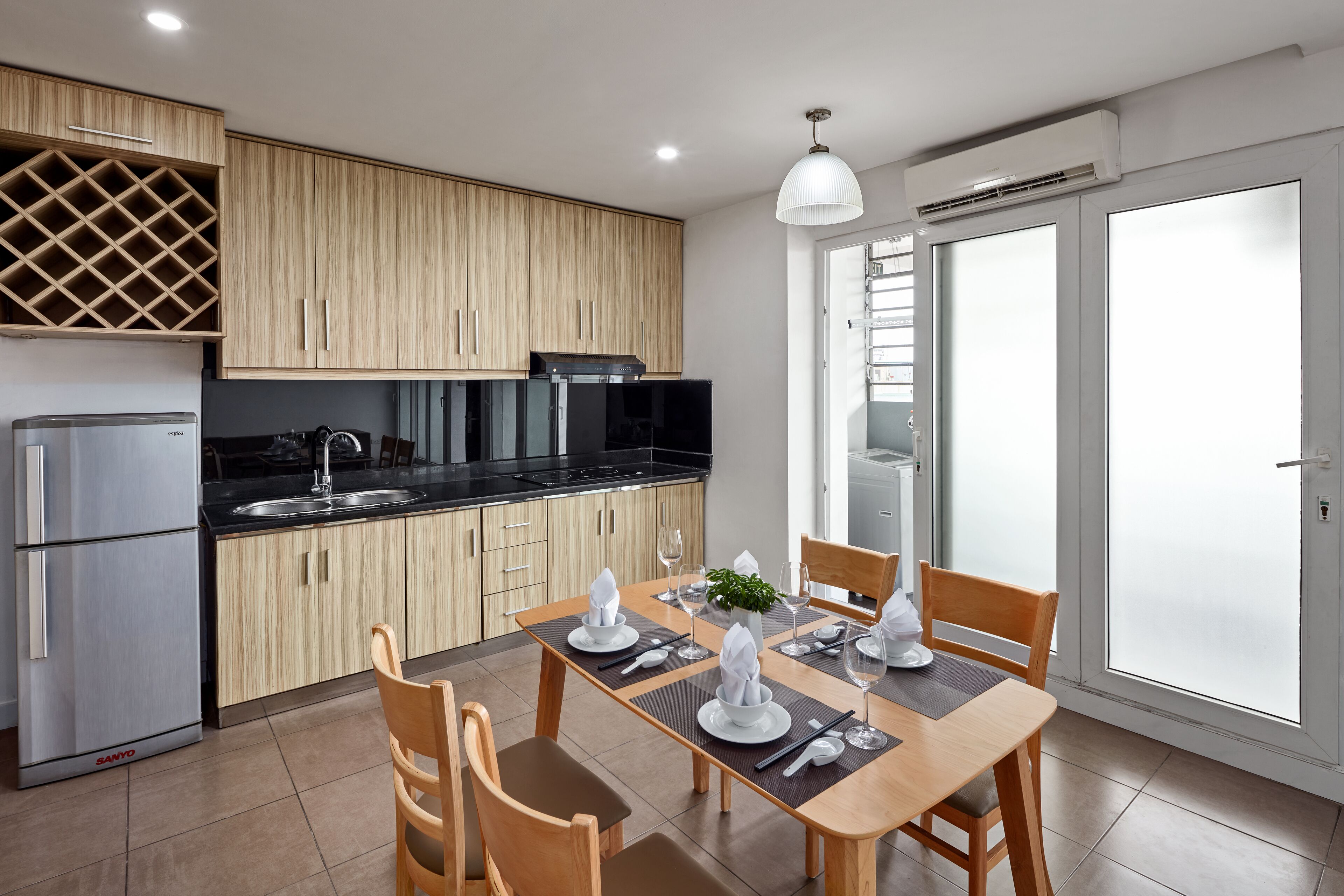 Une cuisine moderne avec des meubles en bois, un meuble-bar intégré et un coin repas avec une table dressée pour quatre personnes.