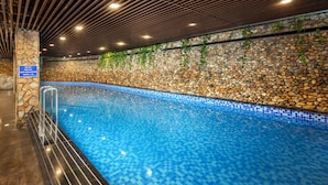 An indoor swimming pool with a stone wall and blue mosaic tiles. - Ravatel Home Bac Giang (Bac Giang)