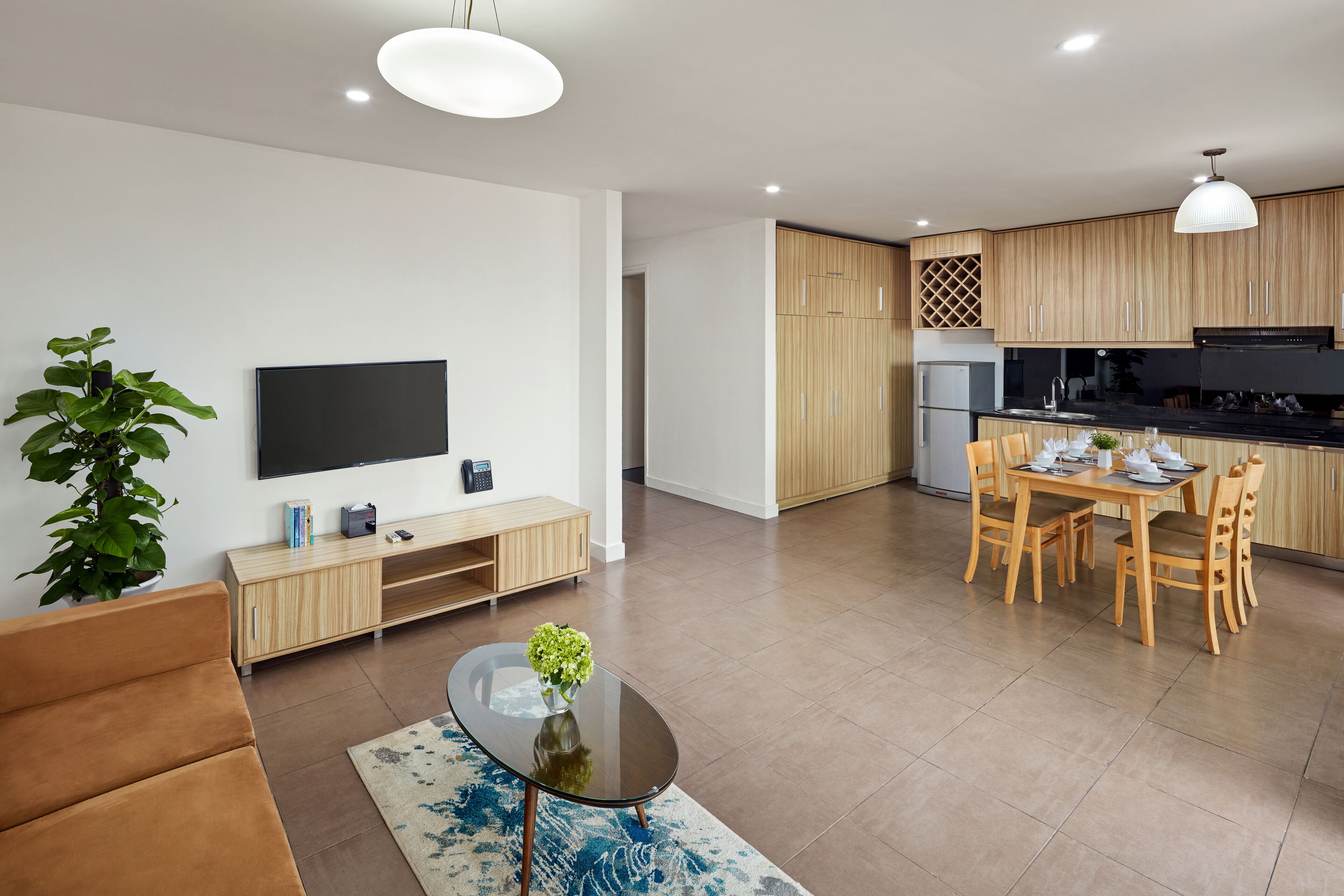 Una sala de estar moderna con un sofá, una mesa de centro con un jarrón, un televisor y un mueble de madera.