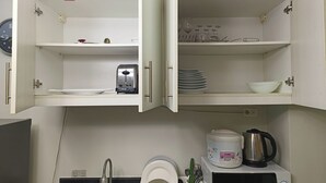 Une cuisine avec des placards ouverts, un grille-pain, une bouilloire et un four à micro-ondes.