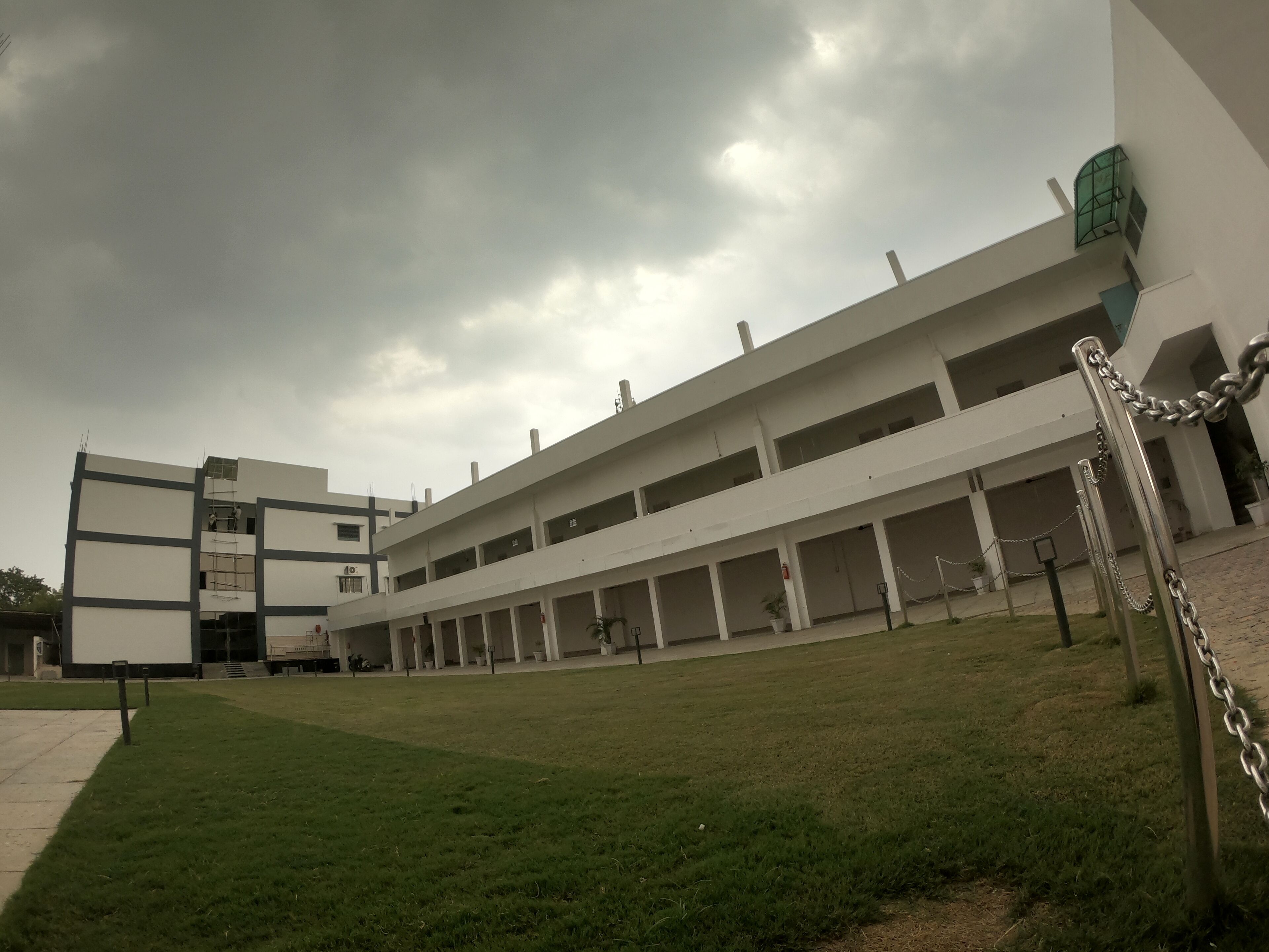 A modern building with multiple floors, a flat roof, and a grassy courtyard.