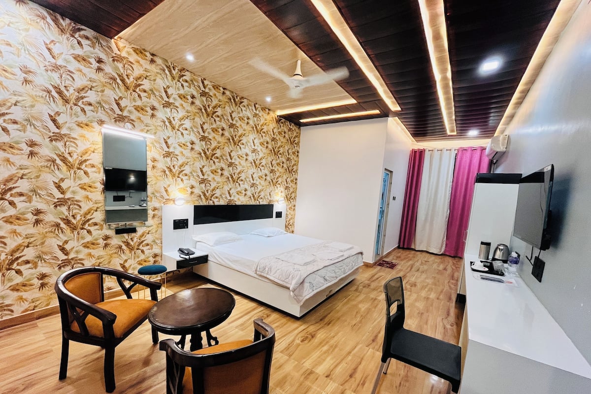 A hotel room with a bed, a desk with a chair, a TV, and a ceiling fan.