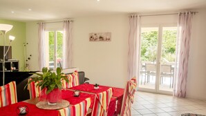 A dining area with a red tablecloth, striped chairs, and a potted plant. - One-storey villa with air conditioning and pool (Bagnols en Forêt)