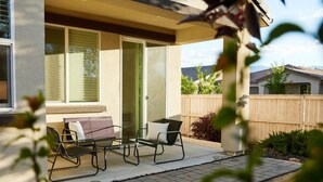 A patio with two chairs and a table, a sliding glass door, and a view of a wooden fence and greenery. - ★NEW★ Upscale House, Tahoe 30-min w/ Cal King (Reno)