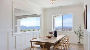 A dining area with a large table and chairs, a view of mountains through large windows, and a potted plant. - PInot Point by AvantStay | Valley Estate Mins to Wineries | Pool + Home Theater (Temecula)