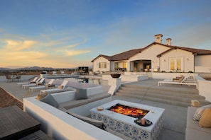 A modern outdoor living area with a fire pit, lounge chairs, and a pool.