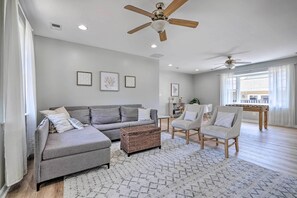 A living room with a grey sofa, a coffee table, and two armchairs. There are ceiling fans, a bookshelf, and a foosball table in the background. - Idyllic Pasadena Retreat with Garden + Hot Tub! (Pasadena)