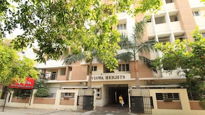 A multi-story building named 'Viswa Heights' with a gated entrance, surrounded by greenery and palm trees. - Viswa Service Apartments (Madurai)